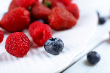Tasty ripe berries on plate close up