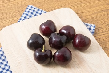 Group of Red Plums on A Wooden Cutting Board