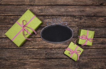 Rustikal verpackte Geschenke in rot grün kariert auf Holz Hintergrund mit Schild im vintage look.