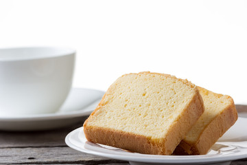 Slice of butter cake with cup of coffee on white background.