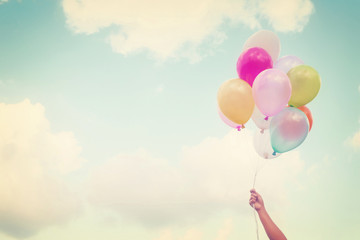 Girl hand holding multicolored balloons done with a retro vintage instagram filter effect, concept...