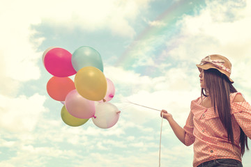 Girl hand holding multicolored balloons done with a retro vintage instagram filter effect, concept...