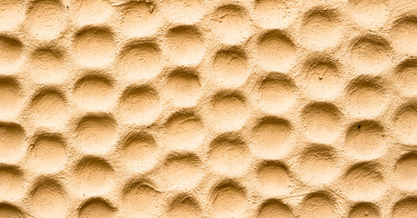 Texture of yellow wall plastered in form of honeycombs