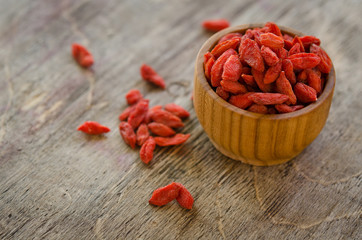 goji berries in bowl and on the table isolated on wooden backgro