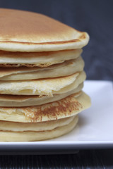 Stack of pancakes on dark wooden background close up