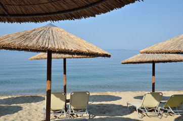 Beach straw parasols and pairs of chairs