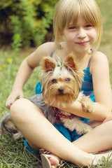 Girl 6 years old on the grass holding  Yorkshire Terrier