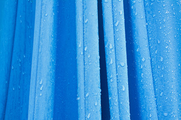 Fototapeta Fragment złożonego niebieskiego parasola ogrodowego z kroplami 
deszczu obraz