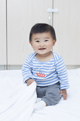 Fototapeta premium Cute Chinese baby boy sitting on a white blanket