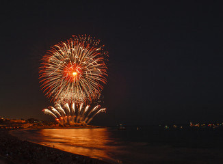 Fireworks display over sea with reflections
