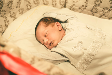 The newborn baby boy sleeping in his bed