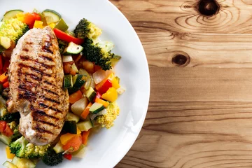 Poster Grilled chicken fillet, breast with cooked vegetable Tomatoes, Carrots, Peppers, Courgettes, brocoli on plates. © grinchh