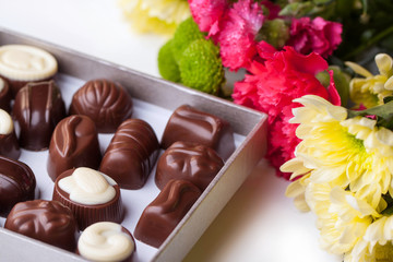 Obraz na płótnie Canvas chocolate candy and flowers over white