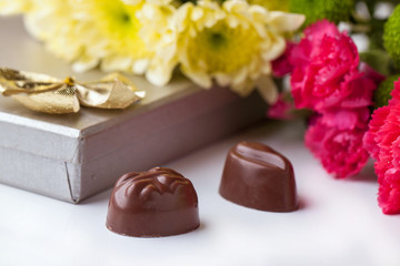 Fototapeta na wymiar chocolate candy and flowers over white