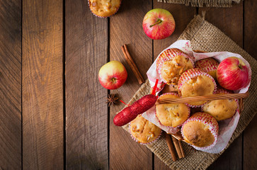 Tasty muffins with apple and cinnamon in basket on a wooden background. Top view