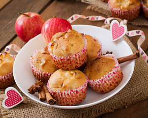 Tasty muffins with apple and cinnamon on a wooden background