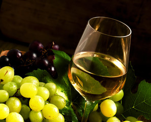 White wine and green grapes in a wicker basket in a wine cellar,