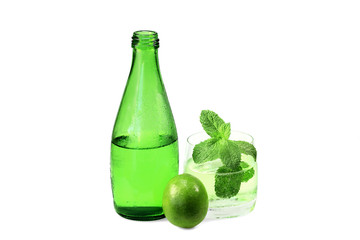 Bottle and glass of sparkling mineral water with lime and meliss