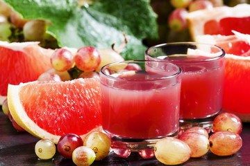 Fresh juice of red grapes and grapefruit on a dark background, s