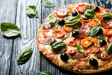Pizza with salami, olives and basil