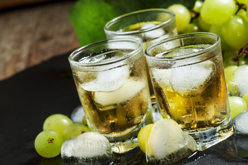 Cold grape juice with ice on dark background, selective focus