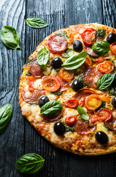 Pizza with salami, olives and basil