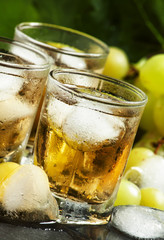Cold grape juice with ice on dark background, selective focus