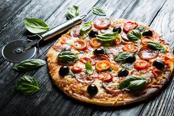 Pizza with salami, olives and basil