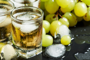 Cold grape juice with ice on dark background, selective focus