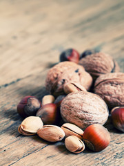 Walnuts, hazelnuts and pistachios on a wooden table, toned image