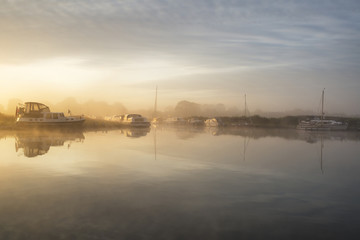 Fototapeta na wymiar Stunning foggy Summer sunrise over peaceful river landscape in E
