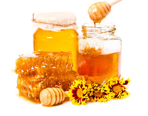 Honeycomb and jars of honey with stick and flowers isolated on w