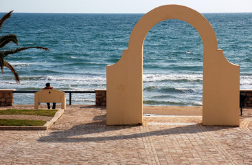 Arco sul mare con persona in panchina
