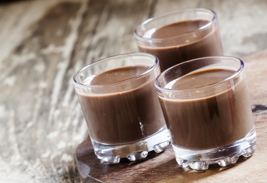 Liquid chocolate in a glass on the old wooden background, select