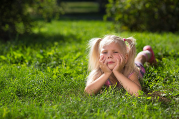 Fototapeta premium little girl lying on green grass