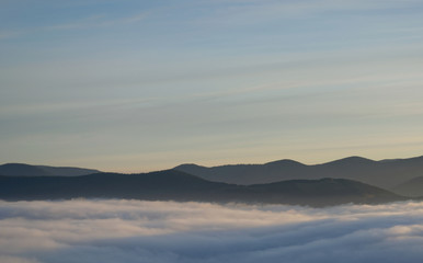 Fototapeta na wymiar View of fog down in the valleys at sunrise in mountains Carpathians in Ukraine