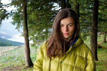 Bust portrait of girl in yellow down jacket in the autumn mountains with mist in the valleys