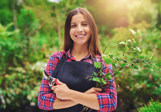 Smiling Young Female Gardener Pruning The Plants