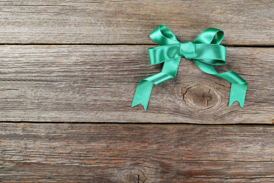 Green bow on grey wooden background