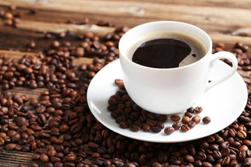 Cup of coffee with coffee beans on a brown wooden background