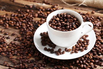 Coffee beans in cup on a brown wooden background