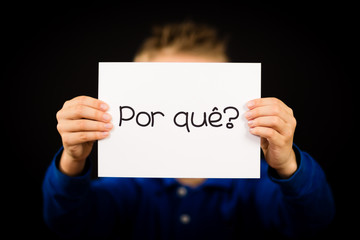 Child holding sign with Portuguese word Por Que - Why