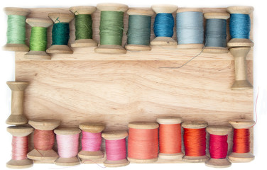 color thread for sewing on  spools on a wooden background, handcraft top view