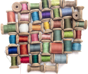 thread for sewing on wooden spools on a white background, handcraft top view
