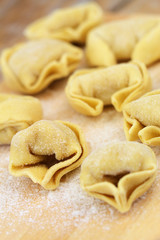 Uncooked tortellini on wooden board
