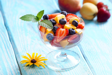 Slatky salad with a sprig of mint in the bowl of glass. Blue background.