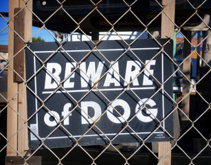 beware of dog sign behind chain link fence
