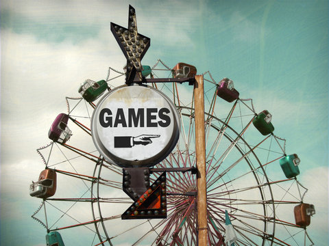aged and worn vintage photo of games sign with ferris wheel