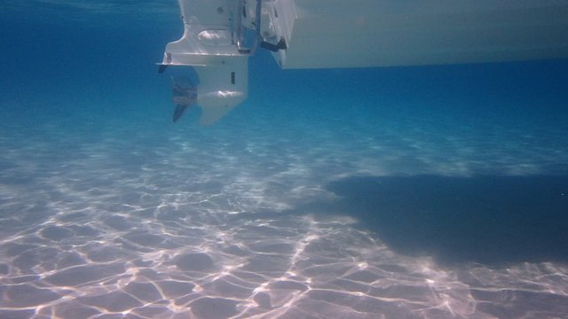 Boat engine with propeller, filmed underwater from very close. Sea is beautiful blue-white colour.