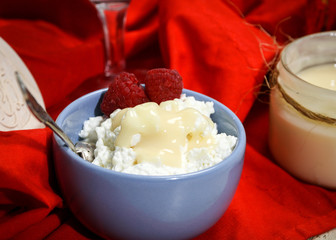 Little bowl of fresh farmer cream cheese with raspberries; topped with condensed milk jam 
